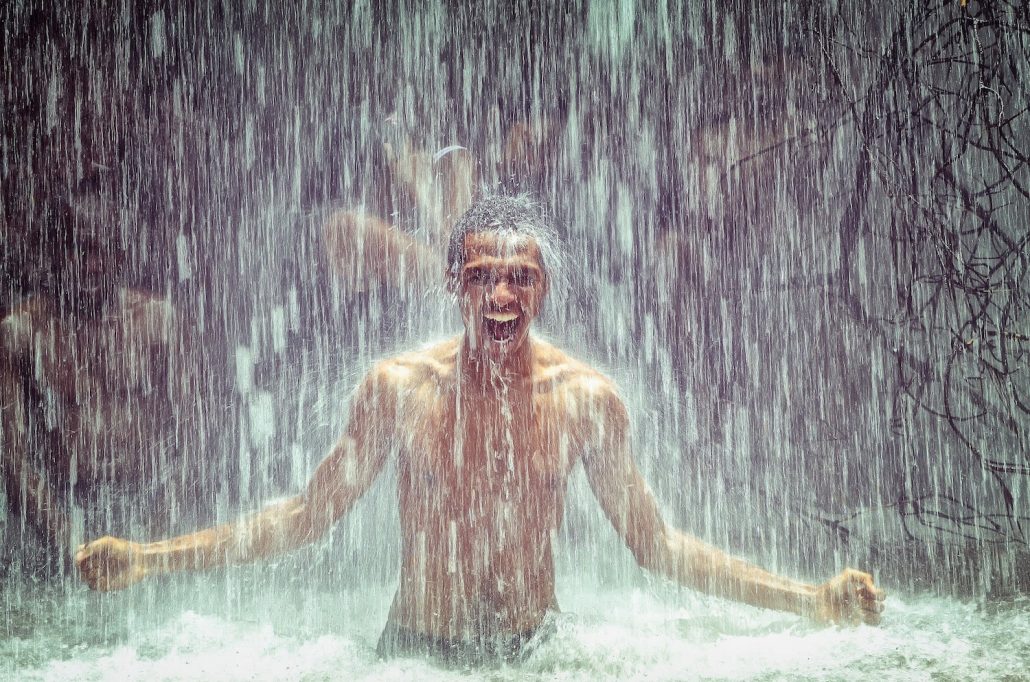 man under waterfall-min